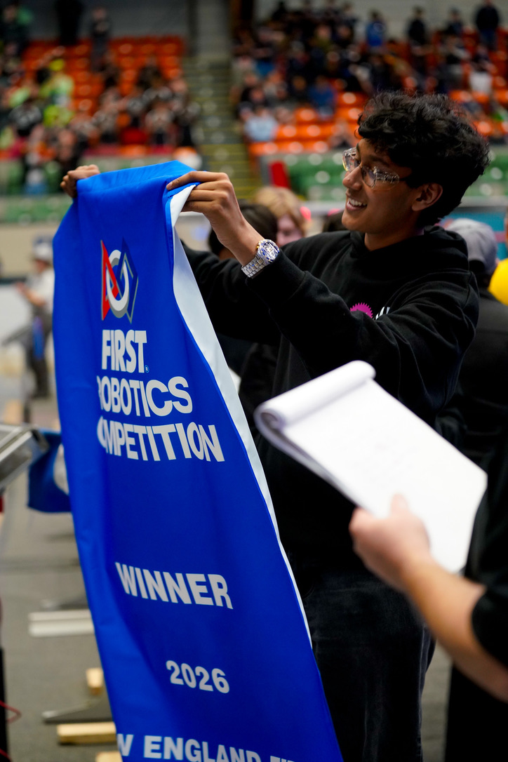 Vishnu holding the 2026 FIRST Robotics Competition New England winner banner